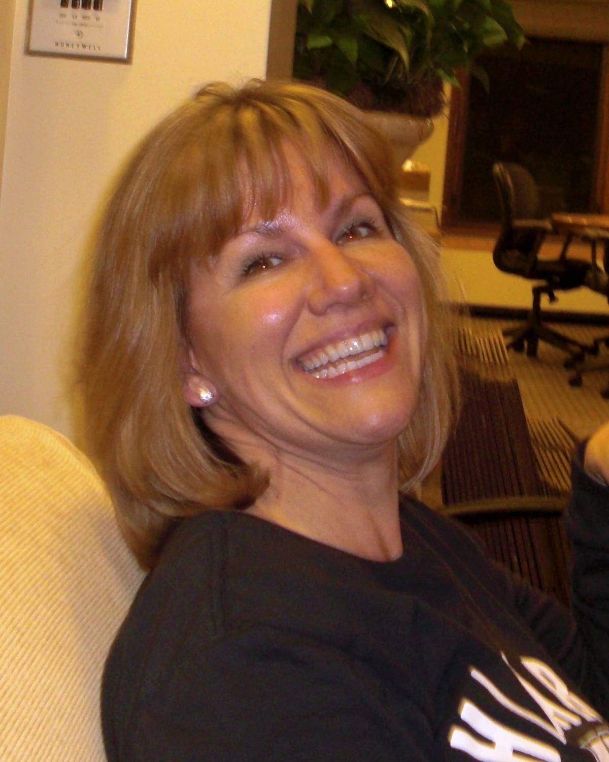 Gayle Bulls Dixon laughing on a sofa, wearing a Harvard sweatshirt, 2008
