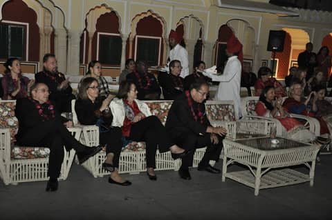 Evening reception in palace courtyard, guests seated on white cane sofas
