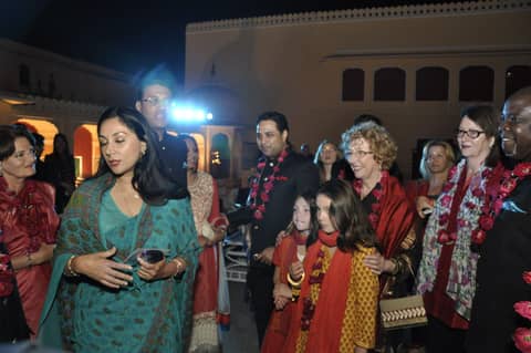 Guests in saris and garlands arriving at night palace event