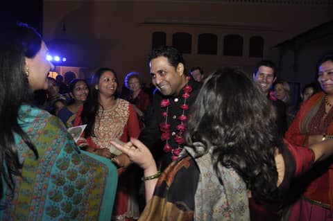 Crowd mingling at night, women in saris, garlands