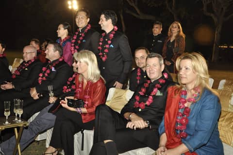 Seated group in garlands at night reception, champagne glasses