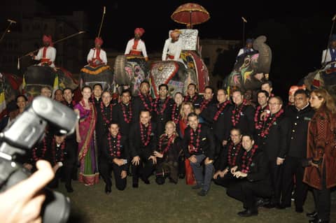 Large group photo in front of row of decorated elephants (camera in foreground)