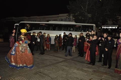 Folk dancer performing at night, tour buses behind