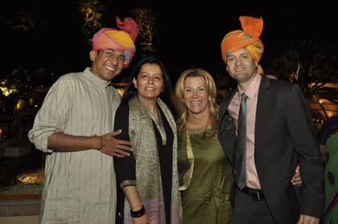 Four people, two men in orange/pink turbans, two women; Gayle in green