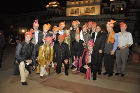 Large group in turbans in front of a lit palace