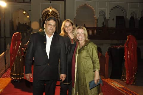 Three guests on red carpet inside palace hall