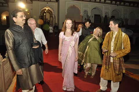 Guests walking in palace hall, man in kurta in front