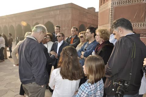 Group gathered in red sandstone courtyard, guide talking