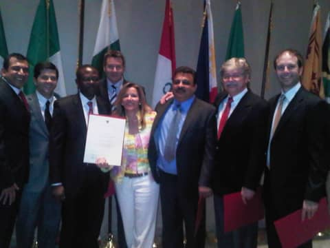 Group holding certificates in front of national flags