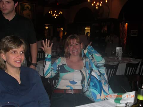 Two women at restaurant table, one waving