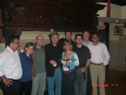 Group of eight standing in front of carved wooden mantel