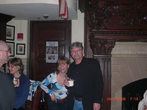Three people by doorway, woman in patterned top in middle